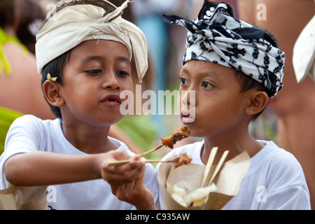 Bali Ubud. Due giovani amici condividere il pollo satay presso il Nyepi celebrazioni in Ubud. Foto Stock