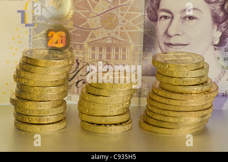 Uno e due libbre di monete in tre pile di fronte venti pound nota Foto Stock