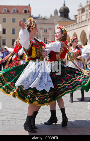 In Polonia, a Cracovia. Lucidare le ragazze in costumi tradizionali balli in piazza del mercato. Foto Stock