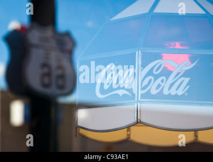 La riflessione in un ristorante di finestra che mostra una Coca Cola lampada da tavolo con un percorso 66 cartello stradale in background, Williams, Arizona Foto Stock