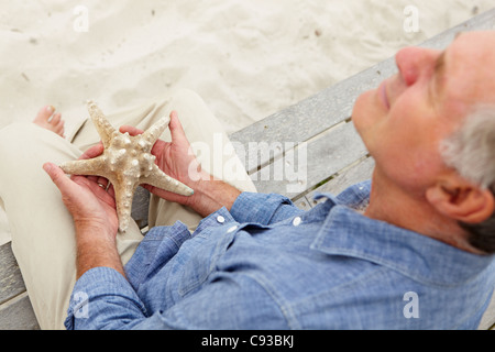 Senior man holding starfish Foto Stock