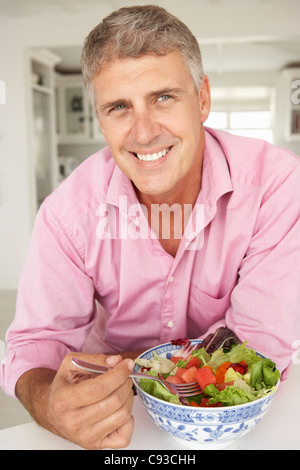 Metà uomo dell'età di mangiare insalata Foto Stock