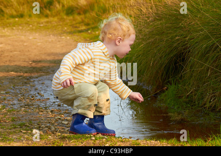 Ragazzo giocando in una pozza e acqua Foto Stock