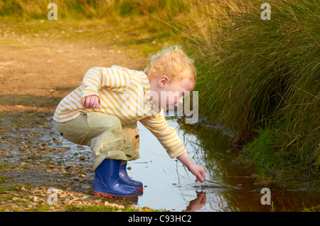 Ragazzo giocando in una pozza e acqua Foto Stock