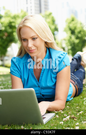 Donna che utilizza computer portatile nel parco della città Foto Stock
