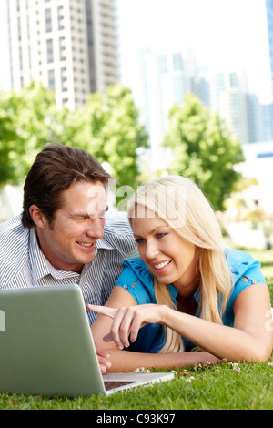 Paio utilizzando laptop nel parco della città Foto Stock