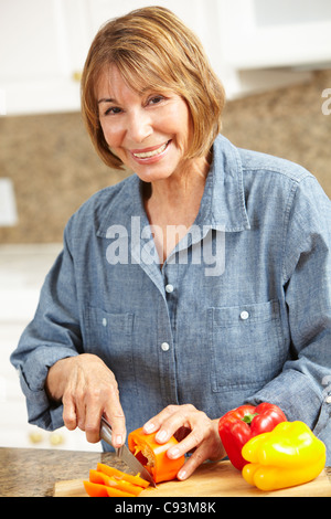 Metà donna età tritare verdure Foto Stock