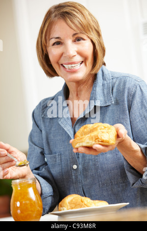 Metà donna età mangiando cornetti Foto Stock