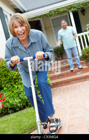 Coppia senior a giocare con i bambini di scooter Foto Stock