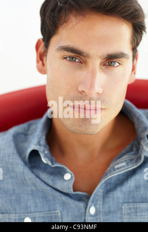 Giovane uomo seduto nella sedia rossa Foto Stock