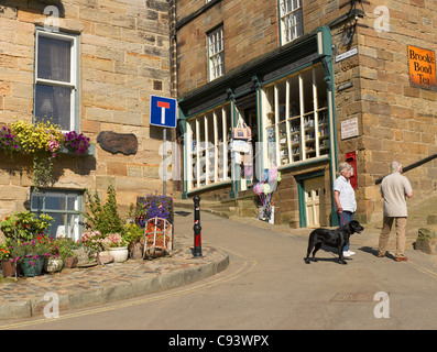 Gente turisti visitatori camminare lungo King Street in estate Robin Hods Bay Village North Yorkshire Inghilterra Regno Unito GB Gran Bretagna Foto Stock