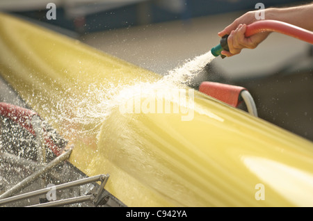 Un vogatore lavando il suo doppio scull canotto. Foto Stock