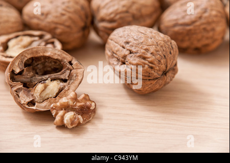 Dettaglio delle noci con una noce sgusciate in primo piano su una superficie in legno Foto Stock