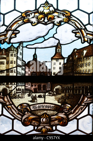 Una finestra di vetro macchiato dal nuovo municipio con una illustrazione della Mary's Square a Monaco di Baviera, Germania. Foto Stock