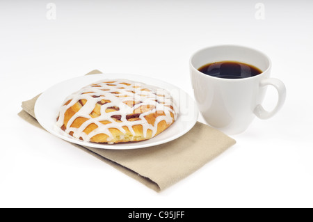 Iced pasticcino Danese sulla piastra bianca con un panno assorbente e tazza di caffè nero su sfondo bianco Foto Stock