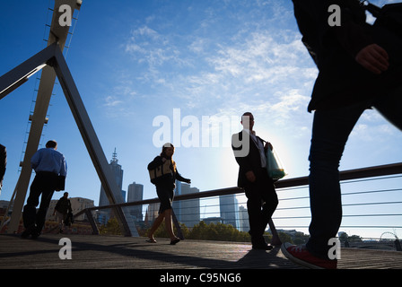 I lavoratori della città attraversando il Southgate Ponte sul Fiume Yarra con lo skyline della città in background. Melbourne, Victoria, Australia Foto Stock