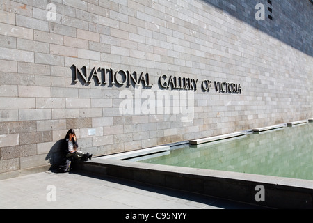 Donna seduta al di fuori della Galleria Nazionale di Victoria a Melbourne, Victoria, Australia Foto Stock