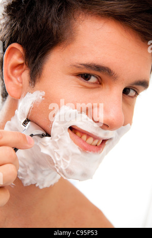 Giovane uomo la rasatura con il rasoio e crema di rasatura nella stanza da bagno Foto Stock