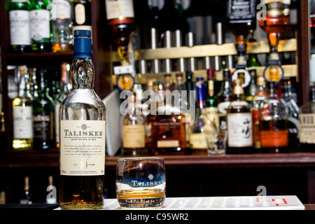 Un bicchiere e una bottiglia di Talisker single malt whisky insieme sulla barra presso un pub locale Tickety Boo è nel centro di Dundee, Regno Unito Foto Stock