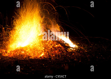Il fuoco con le fiamme e scintille. Colore arancione intenso, giallo bagliore del falò contro una notte nera dello sfondo. Foto Stock