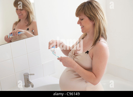 Donna incinta spazzolare i suoi denti. Ella è di 35 settimane di gravidanza. Foto Stock
