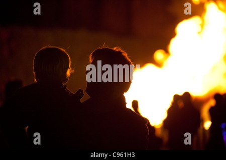 Famiglie stagliano dalle fiamme guardando un falò su Guy Fawkes notte, Wimbledon Park, London, Regno Unito. Foto:Jeff Gilbert Foto Stock