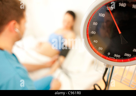 Esame di ostetricia. La levatrice la misurazione di una donna in stato di gravidanza la pressione sanguigna in un centro del parto. Foto Stock