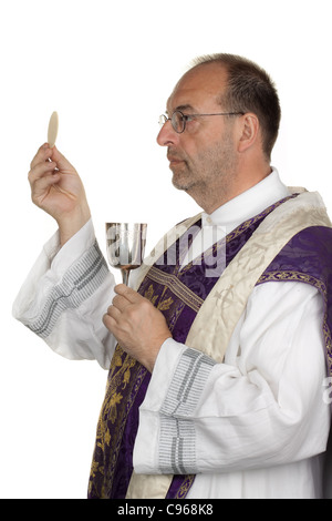 Un sacerdote cattolico durante la comunione nel culto Foto Stock