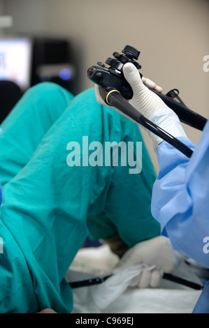 Medico operante un endoscopio per eseguire una colonoscopia procedura di esame in un paziente Foto Stock