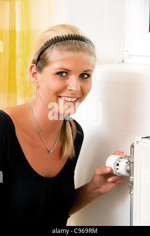 Donna con il radiatore. Risparmiare energia. Il termostato del riscaldatore. Risparmio sui costi di riscaldamento. Foto Stock