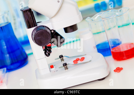 Laboratorio di Scienze sicuro di ricerca di nuovi farmaci, microscopio e pillole di rosso Foto Stock