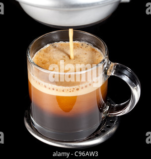 Nero caffè espresso con inebriante della schiuma in un bicchiere di tazza o tazza alta Foto Stock