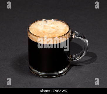 Nero caffè espresso con inebriante della schiuma in un bicchiere di tazza o tazza alta Foto Stock