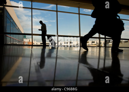 Viaggi in Business Man per controllare la posta elettronica sul telefono cellulare in aeroporto, Philadelphia STATI UNITI D'AMERICA Foto Stock