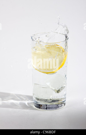 Buccia di arancia cade in un bicchiere con acqua Foto Stock
