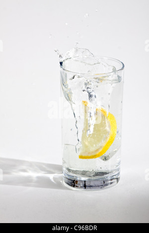 Buccia di arancia cade in un bicchiere con acqua Foto Stock