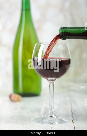 Il vino rosso è versata da una bottiglia in un bicchiere. Foto Stock