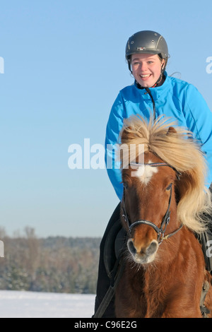 Teen in sella sul dorso di un cavallo islandese in inverno Foto Stock
