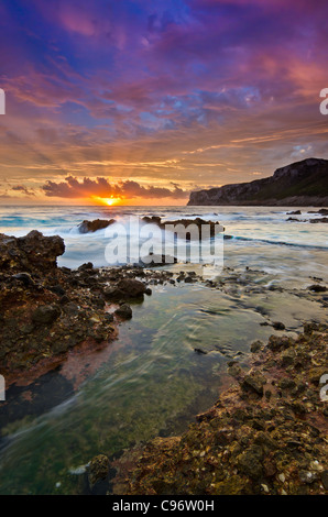 Sunrise seascape con acqua in movimento su rocce e sunray attraverso le nuvole Foto Stock