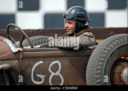 Periodo vestito driver nella vecchia benna trascina auto in attesa di andare sul drag strip. Foto Stock