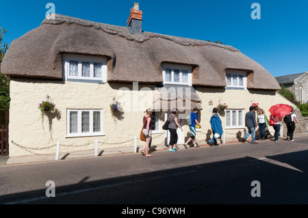 I turisti camminare davanti a un grande cottage con il tetto di paglia a Godshill sull'Isola di Wight in Inghilterra Foto Stock