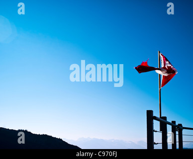 Bandiera canadese soffiando nel vento in corrispondenza della sommità di Whistler Mountain, British Columbia, Canada Foto Stock