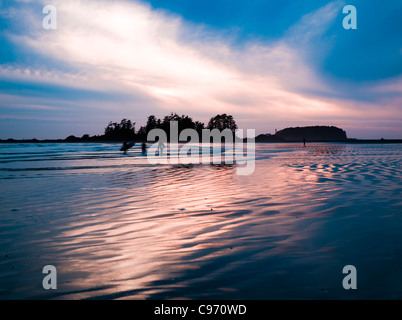 Tramonto con surfers in lontananza sul sud chesterman beach, l'isola di Vancouver, British Columbia, Canada Foto Stock