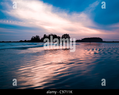 Tramonto con surfers in lontananza sul sud chesterman beach, l'isola di Vancouver, British Columbia, Canada Foto Stock