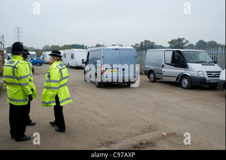 Il 16 novembre 2011. Dale Farm Essex, UK. Consiglio di Basildon i funzionari di polizia hanno partecipato Dale Farm, Basildon, per servire ulteriori avvisi su alcuni viaggiatori che avevano spostato indietro sulla strada sul lato illegale del sito. Gli ufficiali di polizia guarda i veicoli il parcheggio sulla strada in ambito giuridico. Foto Stock