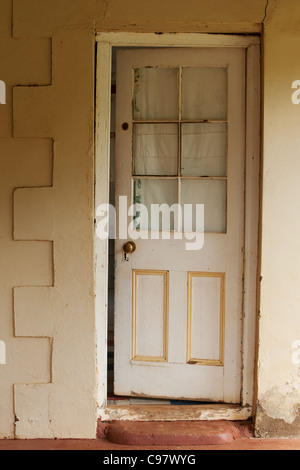 Un weathered porta in legno con cottage vetri in piedi leggermente socchiuse Foto Stock