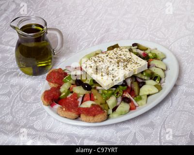 Una insalata greca piastra caraffa di olio di oliva e del vetro sulla tovaglia Foto Stock