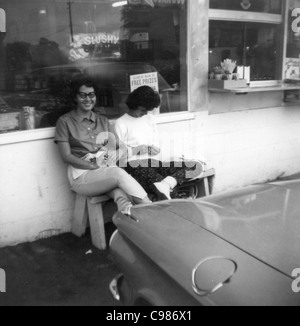 Indiana per la cultura automobilistica degli anni sessanta in bianco e nero colleghe donna seduta di fronte a guidare in sorridente moda donna Foto Stock