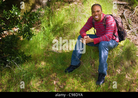 African American college studente seduto su un pendio erboso Foto Stock