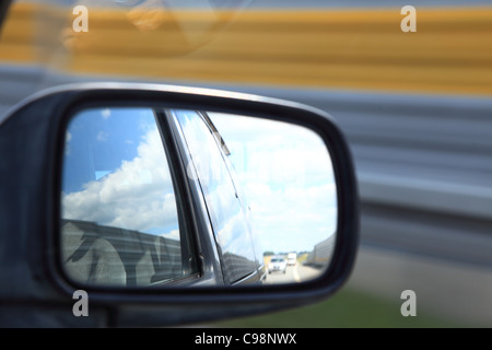 Riflettendo su strada nella veduta laterale specchio di una automobile Foto Stock